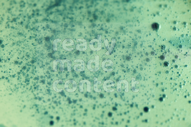 لقطات مقربة لقطرات ألوان مائية خضراء على سطح الزيت على خلفية خضراء