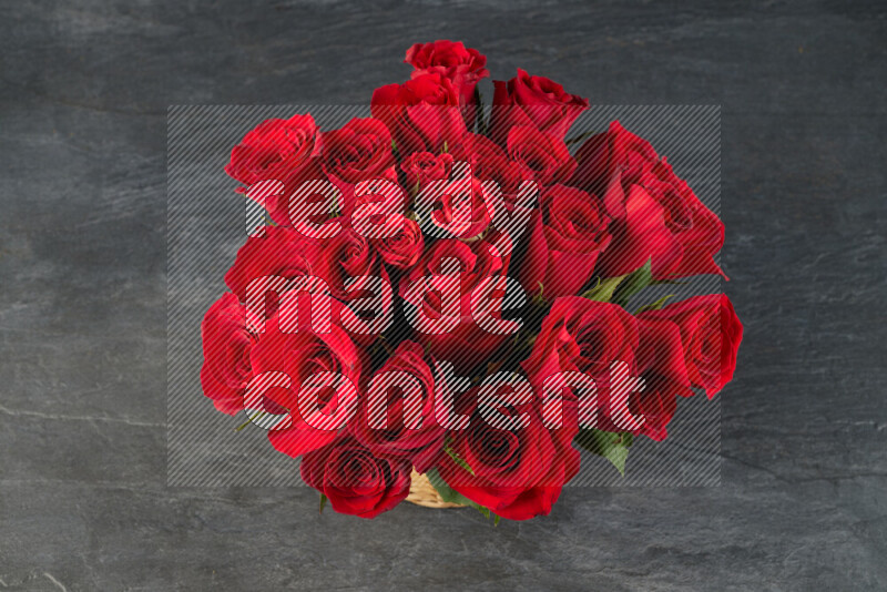 Vibrant red roses in a wicker basket on black marble background