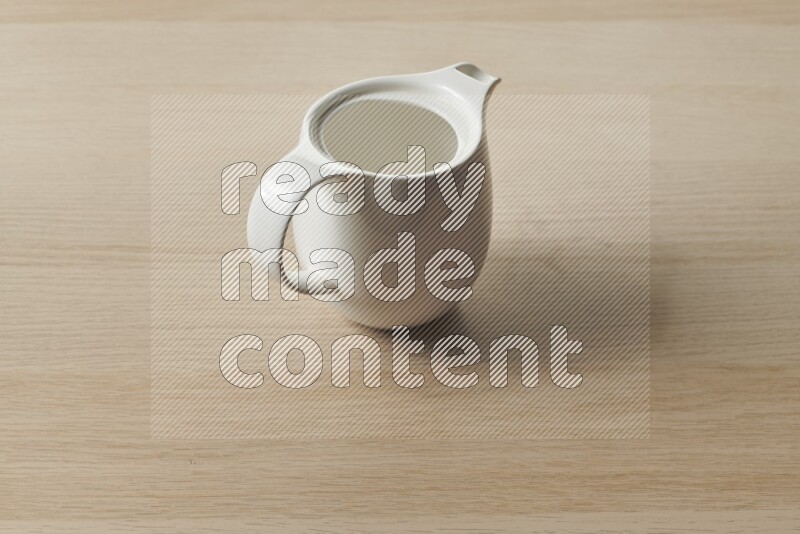 A ceramic milk jug on light wooden background