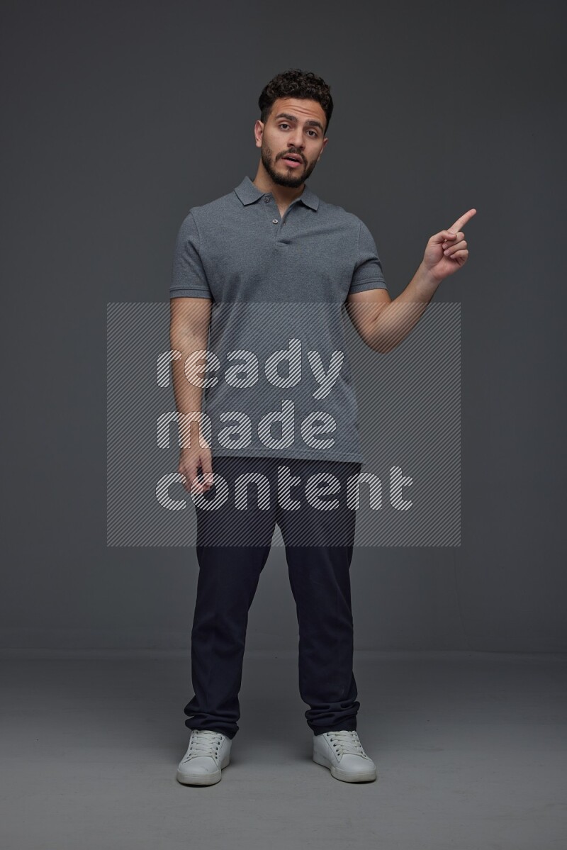 A man wearing casual standing and making multi hand gestures eye level on a gray background