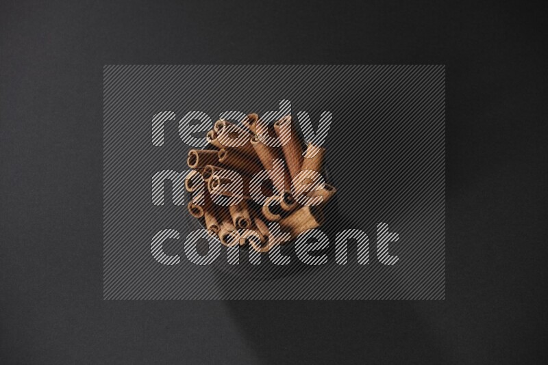 Cinnamon sticks in a black bowl on a black background in different angles
