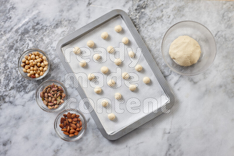 Ghoriba step by step with its ingredient, flour, powdered sugar, ghee and nuts on grey marble background