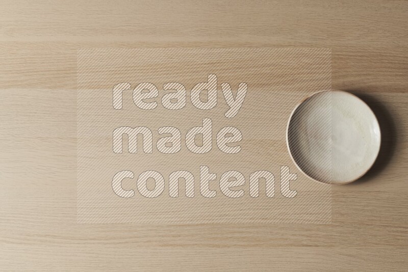 A beige pottery plate on light wooden background