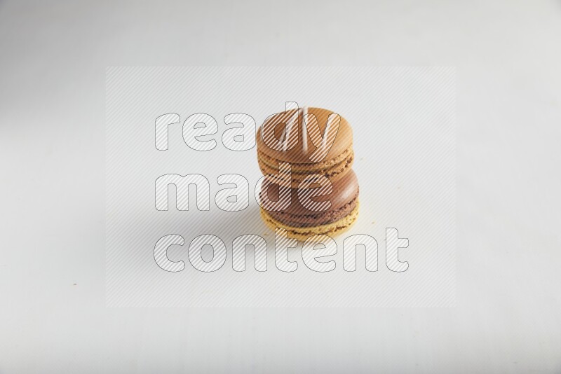 45º Shot of of two assorted Brown Irish Cream, and Yellow, and Brown Chai Latte macarons on white background