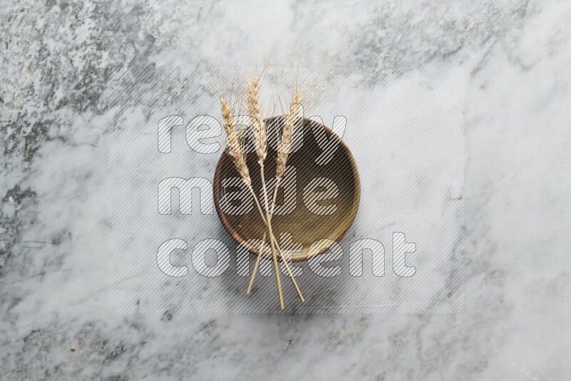Wheat stalks on multicolored pottery oven plate on grey marble background