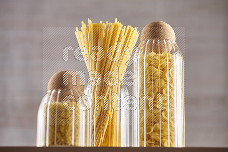 Raw pasta in glass jars on beige background