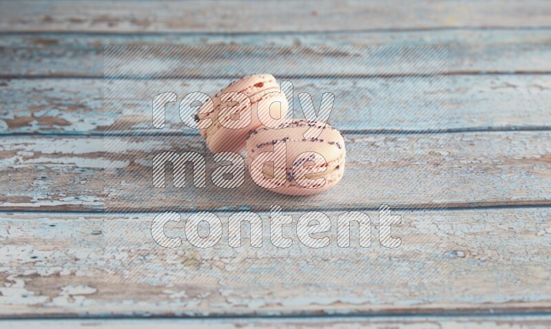 45º Shot of two pink orange blossom macarons on light blue wooden background