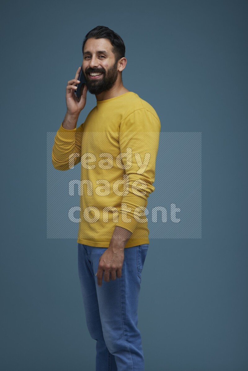 A man having a calling in a blue background wearing a yellow shirt