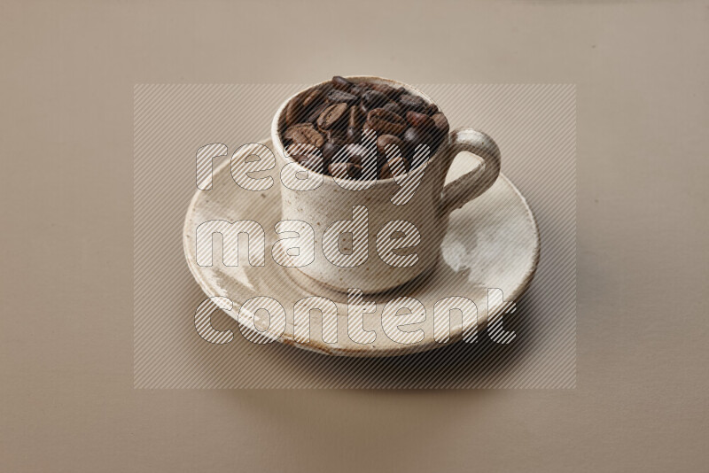 A beige pottery cup full of roasted coffee beans on beige background