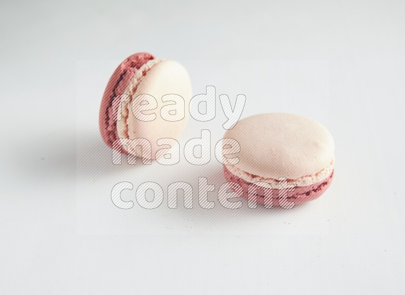 45º Shot of two Pink Litchi Raspberry macarons on white background