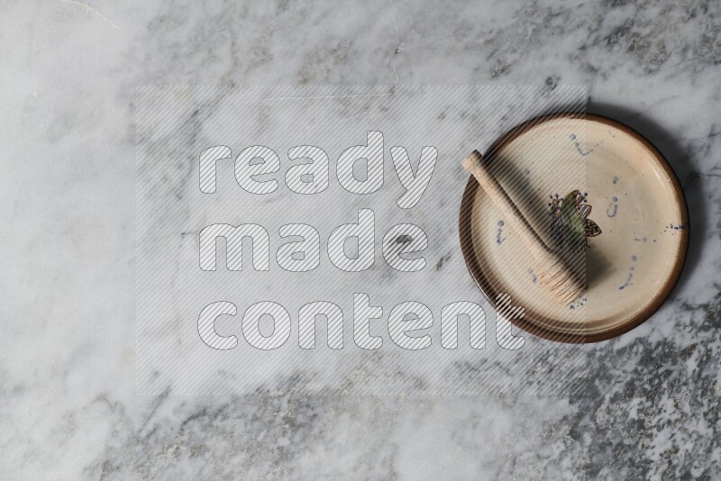 طبق فخاري مزخرف مع ملعقة عسل خشبية بداخله على خلفية من الرخام الرمادي