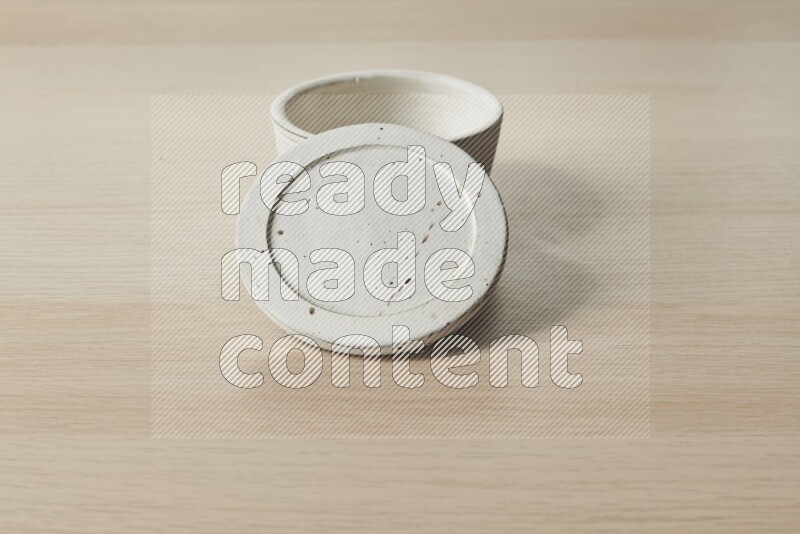 A white pottery bowl on light wooden background