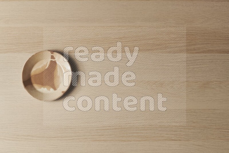 صحن فخاري متعدد الألوان على خلفية خشبية فاتحة