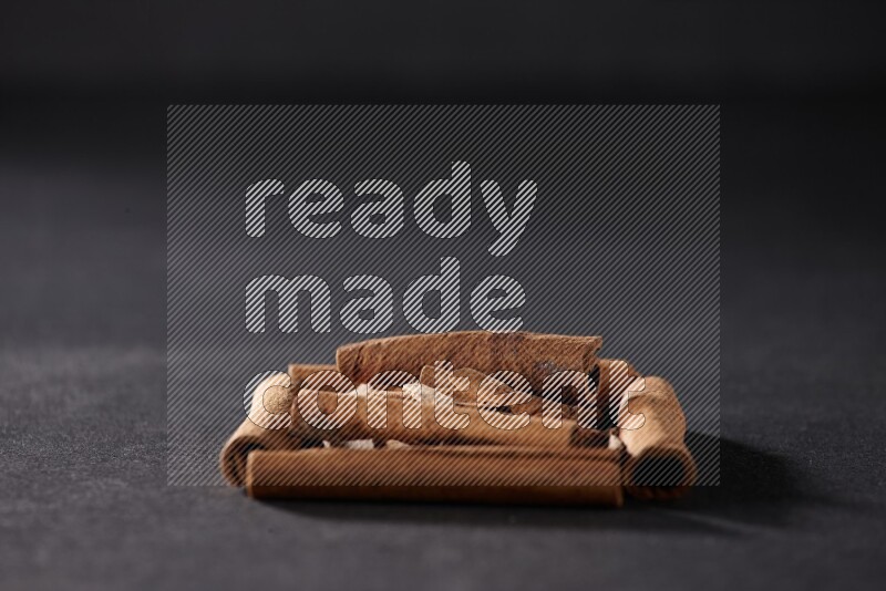 A single square of cinnamon sticks full of cinnamon on black flooring