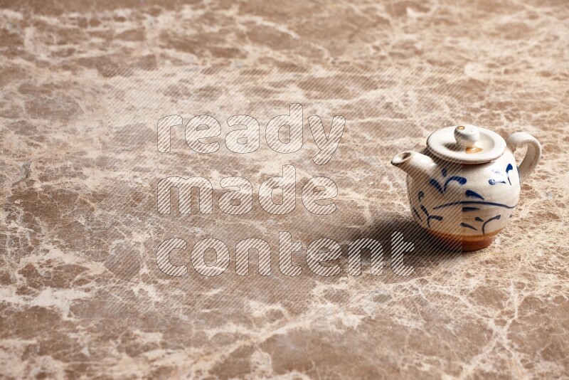 A pottery teapot on beige marble background