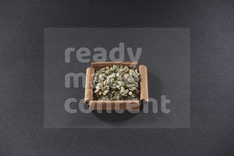 A single square of cinnamon sticks full of Cardamom on black flooring