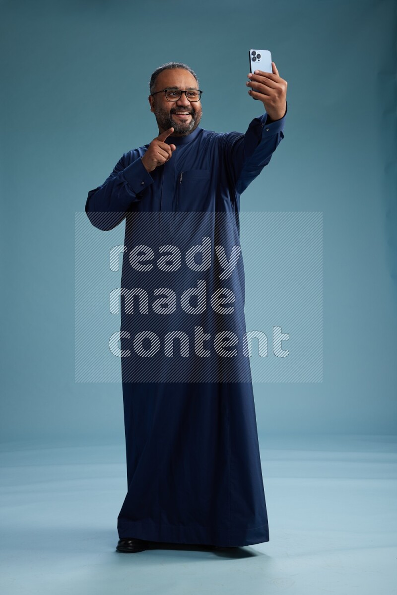 Saudi Man without shimag Standing taking selfie on blue background