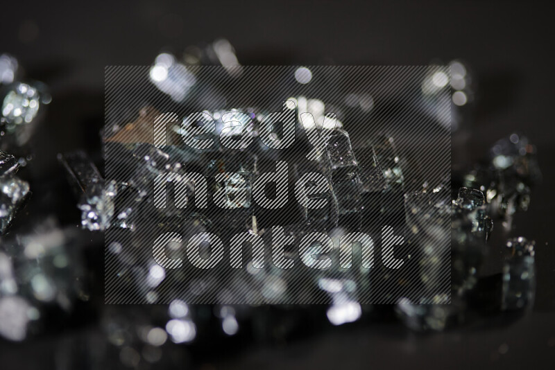 Transparent black fragments of glass scattered on a black background