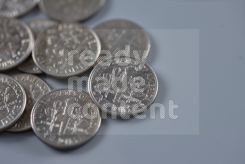 A close-up of scattered United States one dime coins on grey background