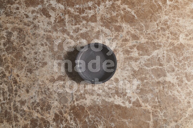 A black pottery bowl on beige marble background