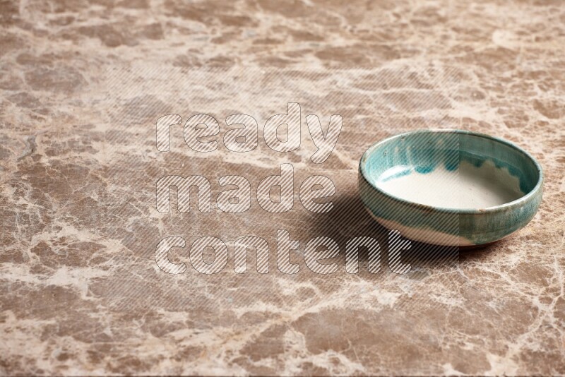 A multicolored pottery plate on beige marble background