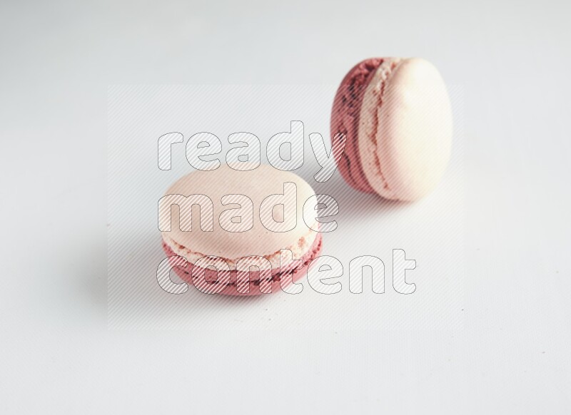 45º Shot of two Pink Litchi Raspberry macarons on white background