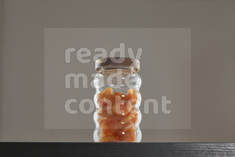 Dried apricots in a glass jar on black background