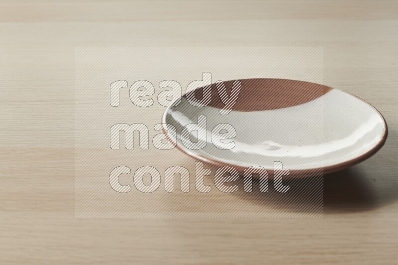 A multicolored pottery plate on light wooden background