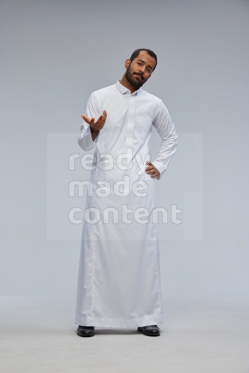 Saudi man Wearing Thob standing interacting with the camera on Gray background