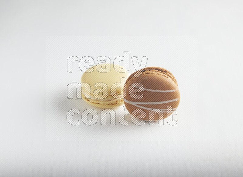 45º Shot of of two assorted Brown Irish Cream, and Yellow Vanilla macarons on white background
