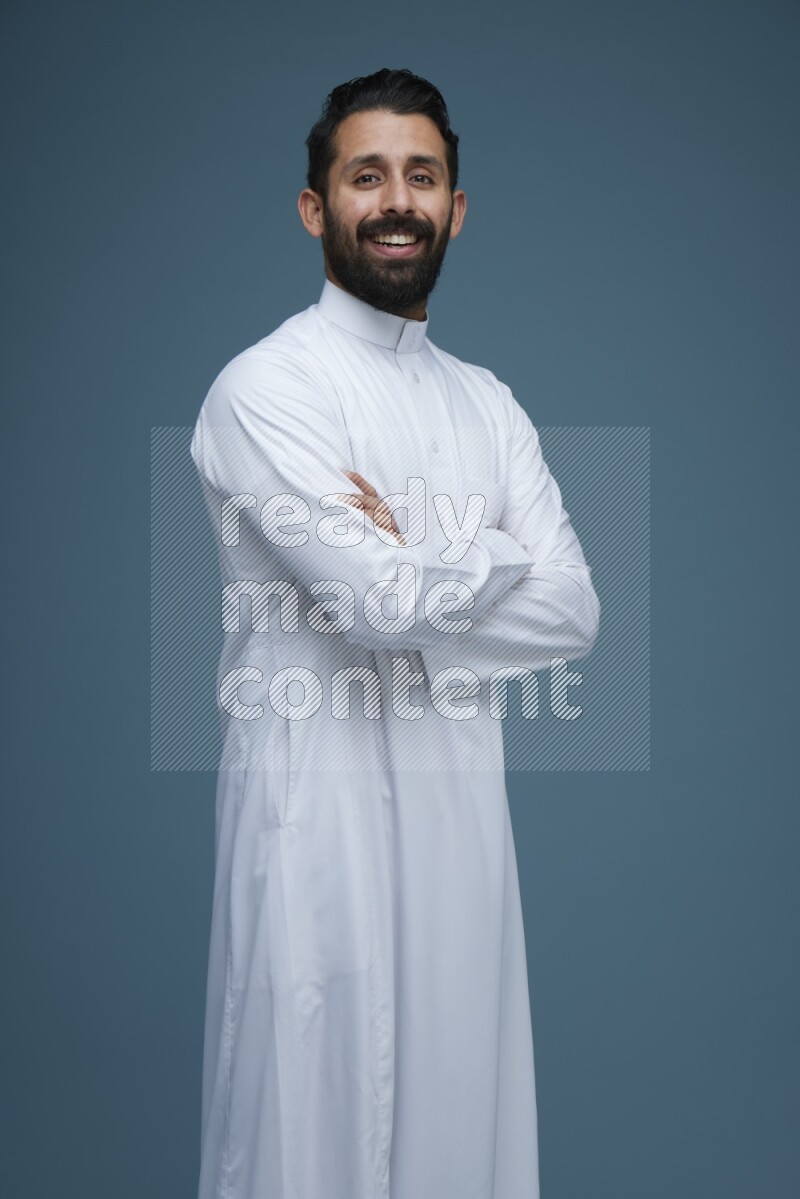 A man posing in a blue background wearing Saudi Thob