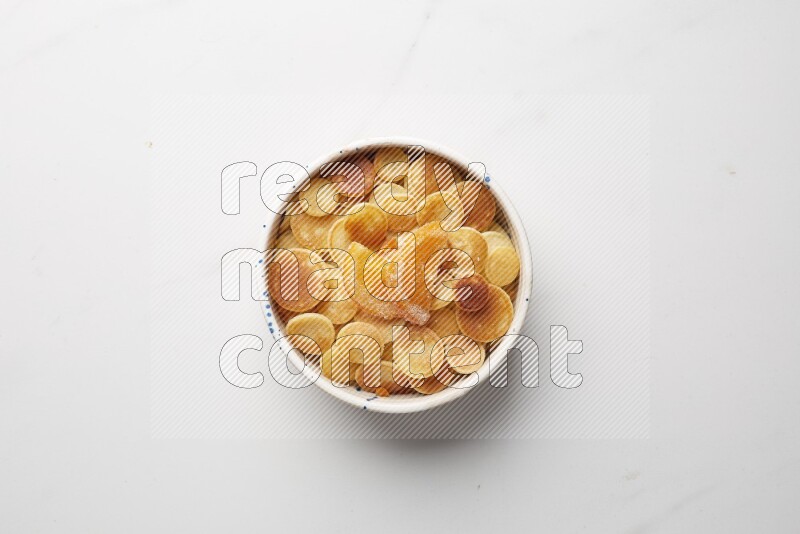 Top-view shot of orange candy cereal pancakes in a round bowl on white background