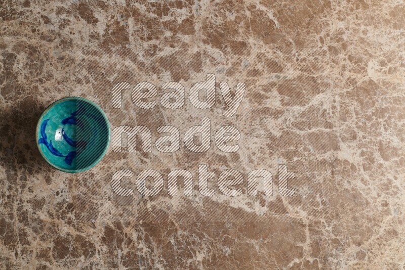 A multicolored pottery bowl on beige marble background