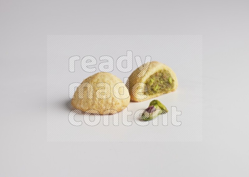 Two Pieces of Maamoul filled with pistachio paste  one of them is cut direct on white background