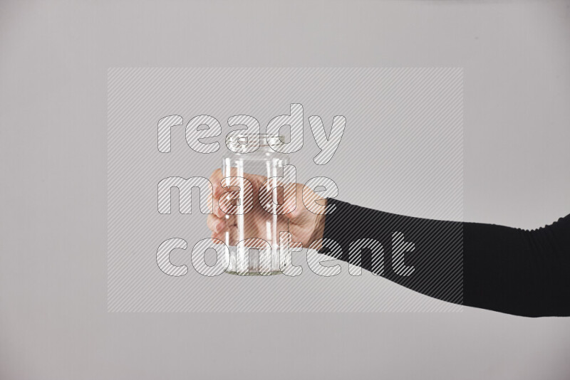 A woman in black abaya holding different glassware in different positions