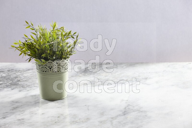 Artificial plant in green decorative pot on grey marble background