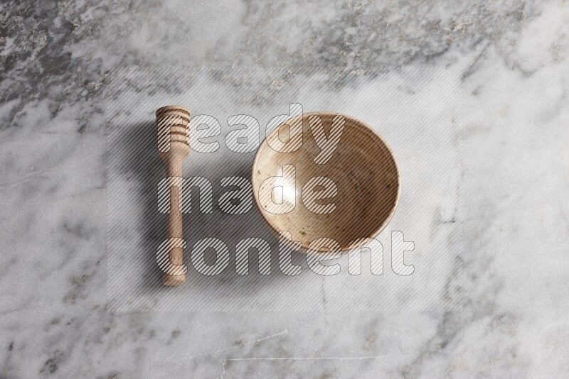 Multicolored pottery bowl with wooden honey dipper on the side on grey marble background