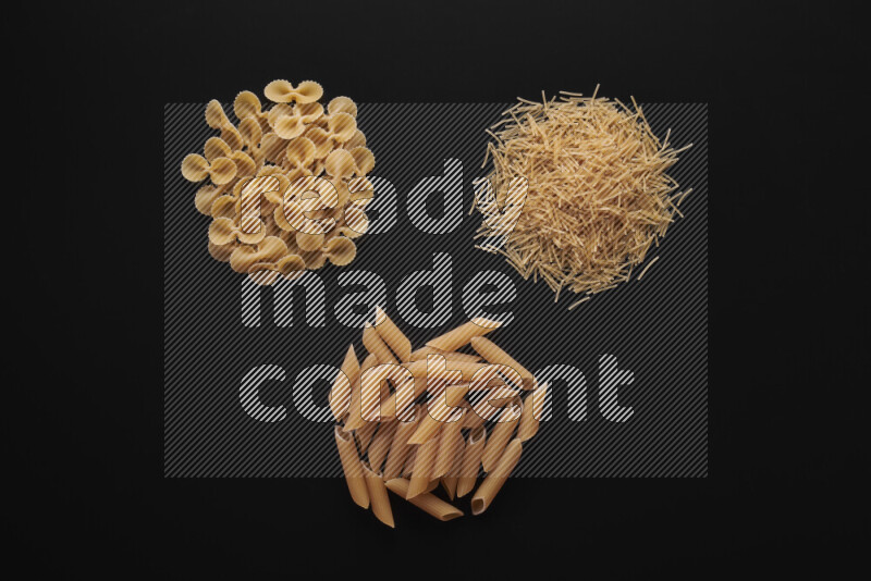 Different pasta types in bunches on black background