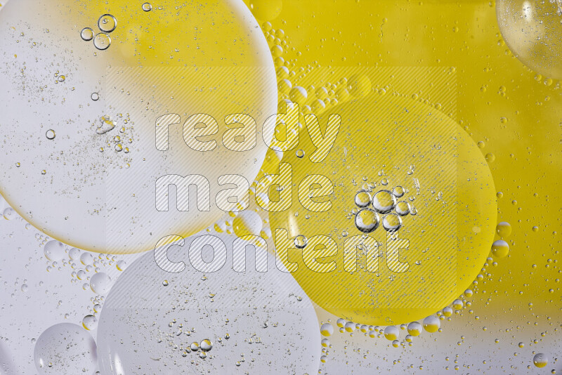 Close-ups of abstract oil bubbles on water surface in shades of white and yellow