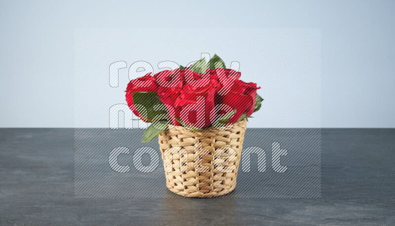 Vibrant red roses in a wicker basket on black marble background