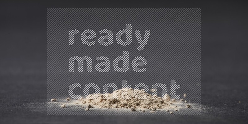 A small pile of garlic powder on a black background