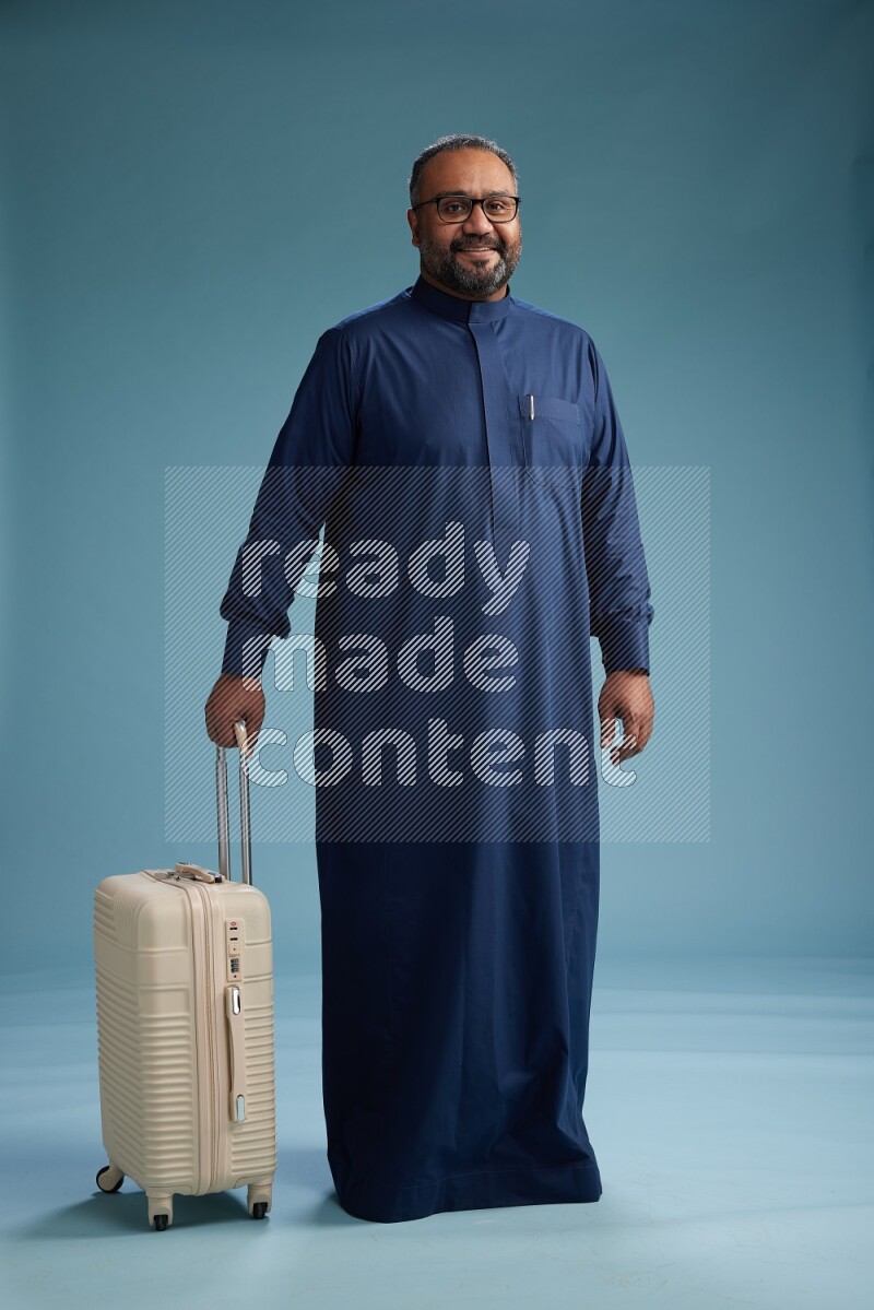 Saudi Man without shimag Standing pulling travel bag on blue background