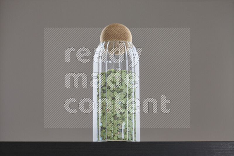 Sequins in a glass jar on black background