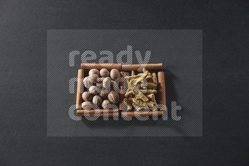 2 squares of cinnamon sticks full of nutmeg and turmeric fingers on black flooring