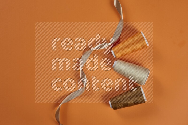 A brown collection of sewing and tailoring tools arranged on a orange background