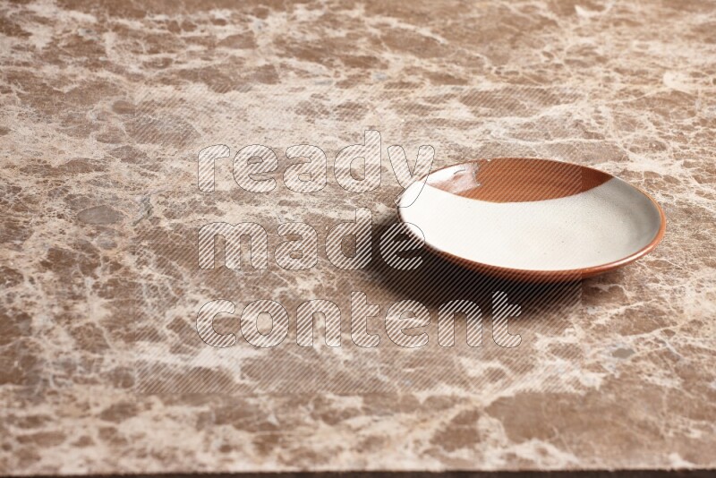 A multicolored pottery plate on beige marble background