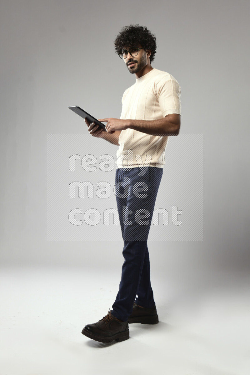 A man wearing casual standing and browsing on a tablet on white background