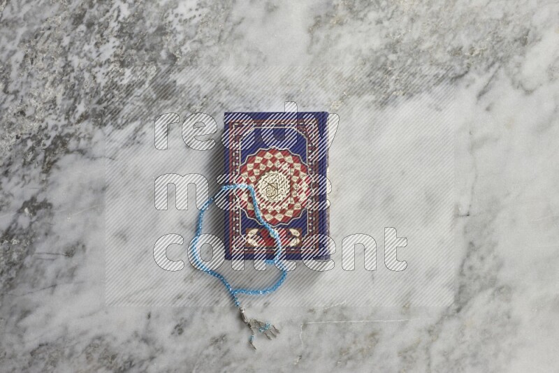 Quran with a prayer beads on grey marble background