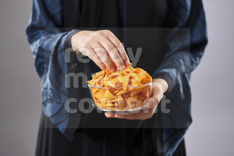 Woman in abaya holding different kinds of snacks in different positions