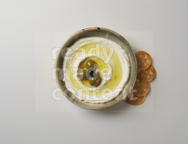 Lebnah garnished with whole olives in a grey pottery plate on a white background